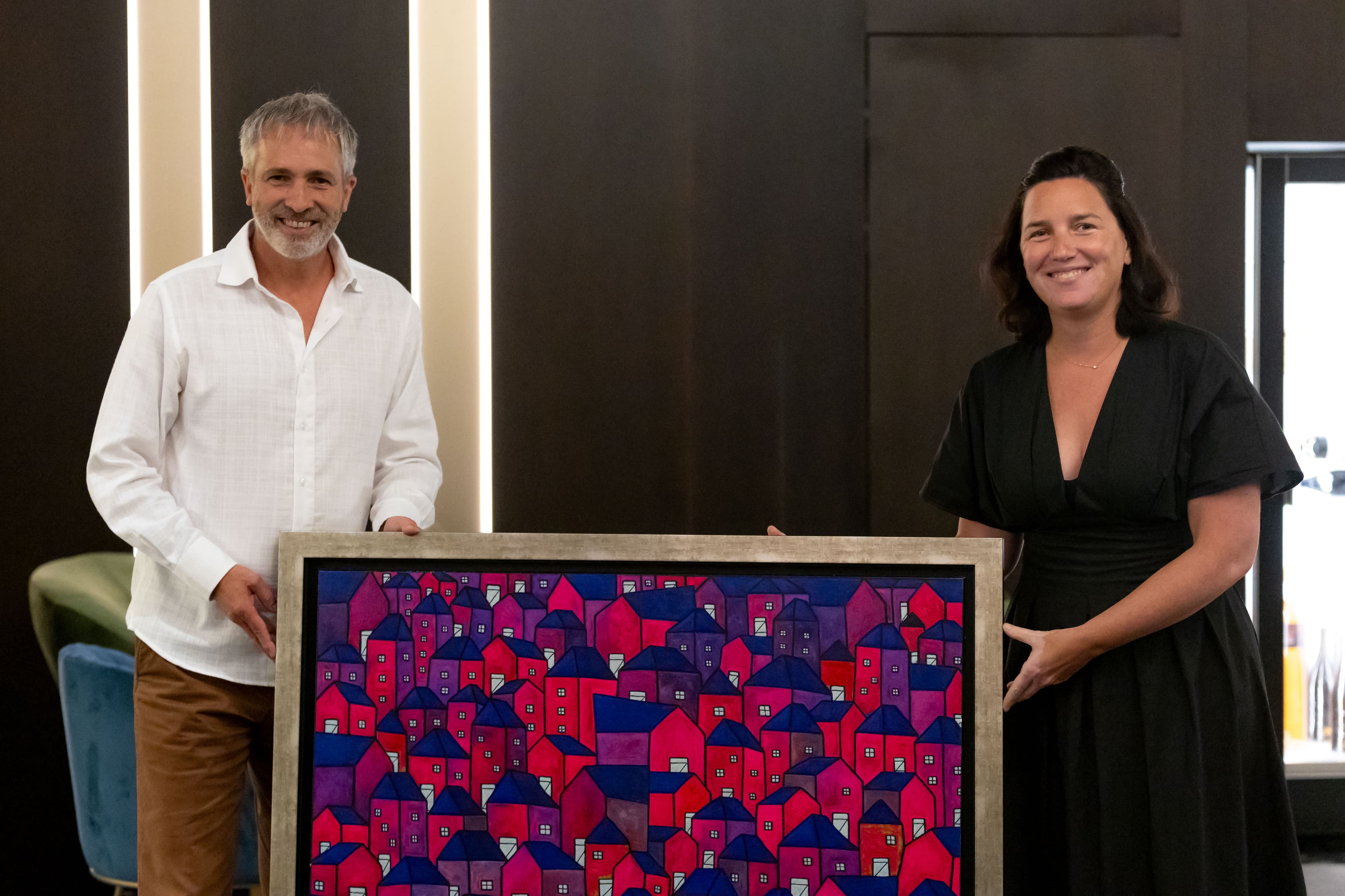 Two people holding a painting