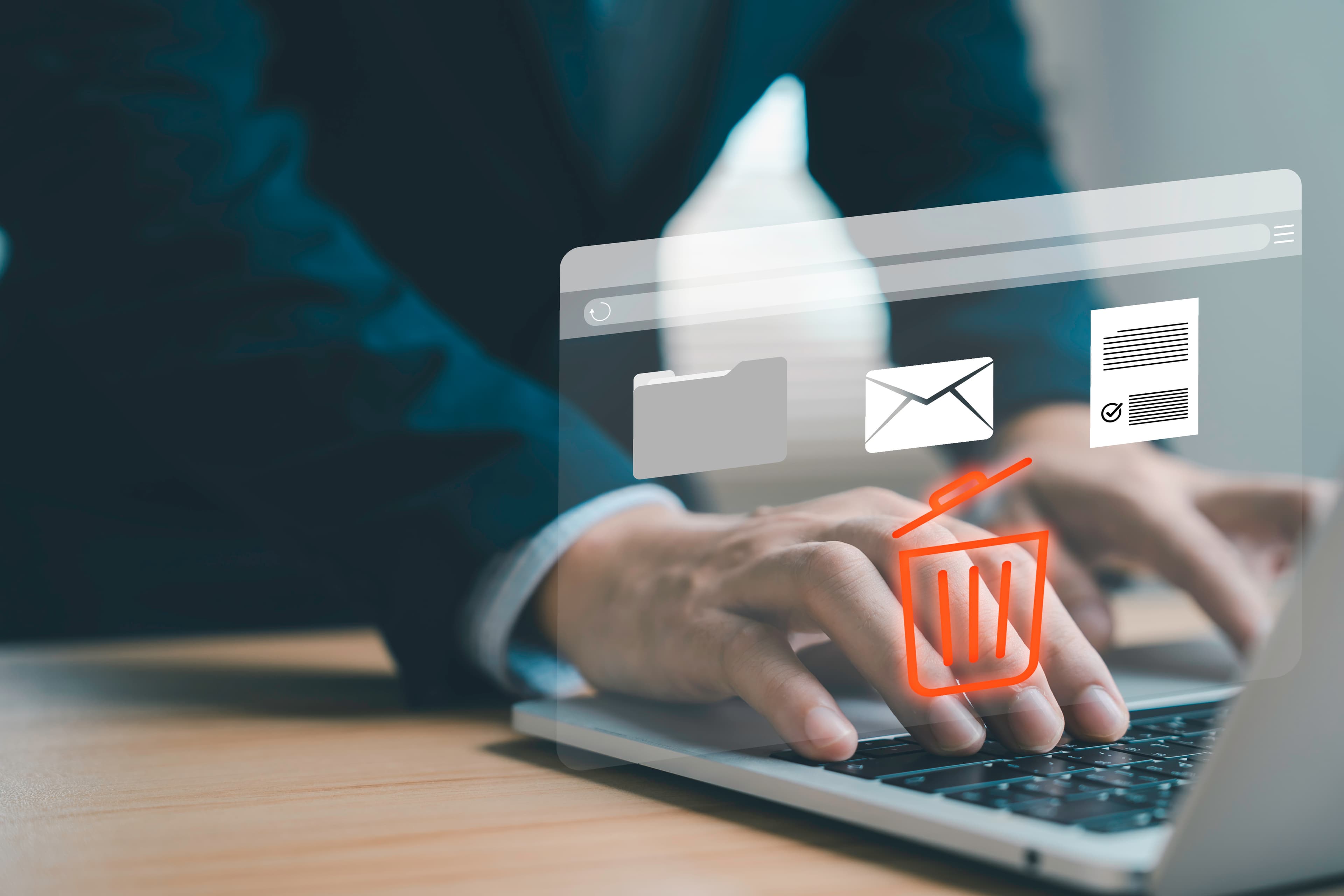 Businessman using laptop with hologram trash bin icon to delete email files and documents